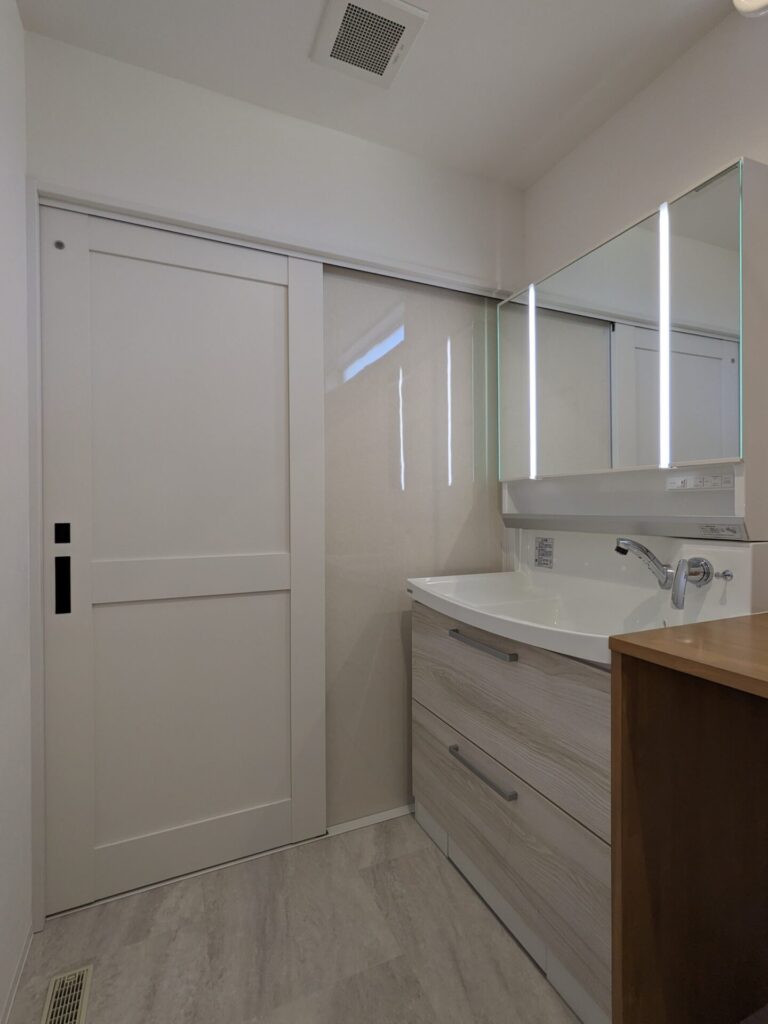 洗面化粧台横の壁は水撥ね対策でキッチンパネルを採用。